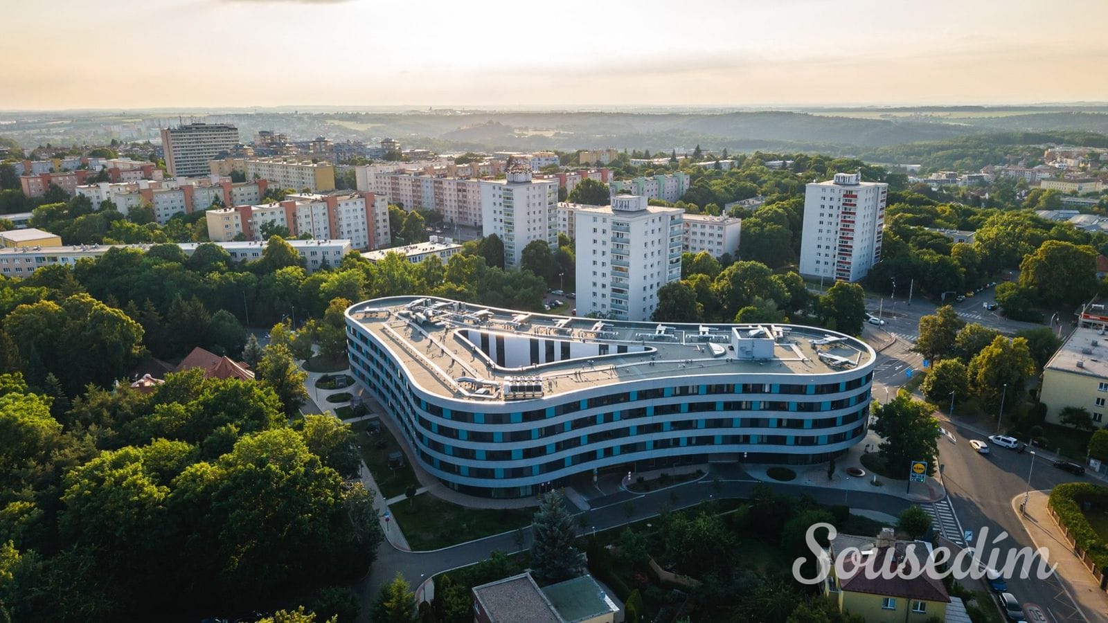 Atrium Petřiny — letecký pohled na dům, okolní zeleň a Petřiny